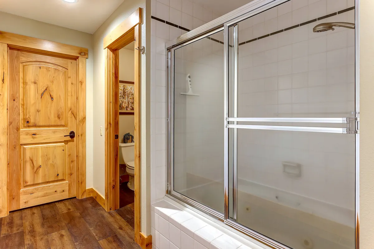 A well-lit bathroom featuring a modern shower enclosure, wooden door, and a thoughtfully arranged toilet area. The space exudes a sense of calm and cleanliness—ideal for freshening up after outdoor activities.