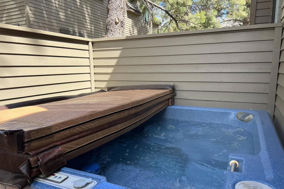 This image features a tranquil hot tub surrounded by a wooden enclosure and walls, creating a semi-private and spa-like atmosphere. The setting suggests relaxation, with the promise of sunset views or starlit soaking sessions, and hints at the comfort and luxury of a private spa experience at home.
