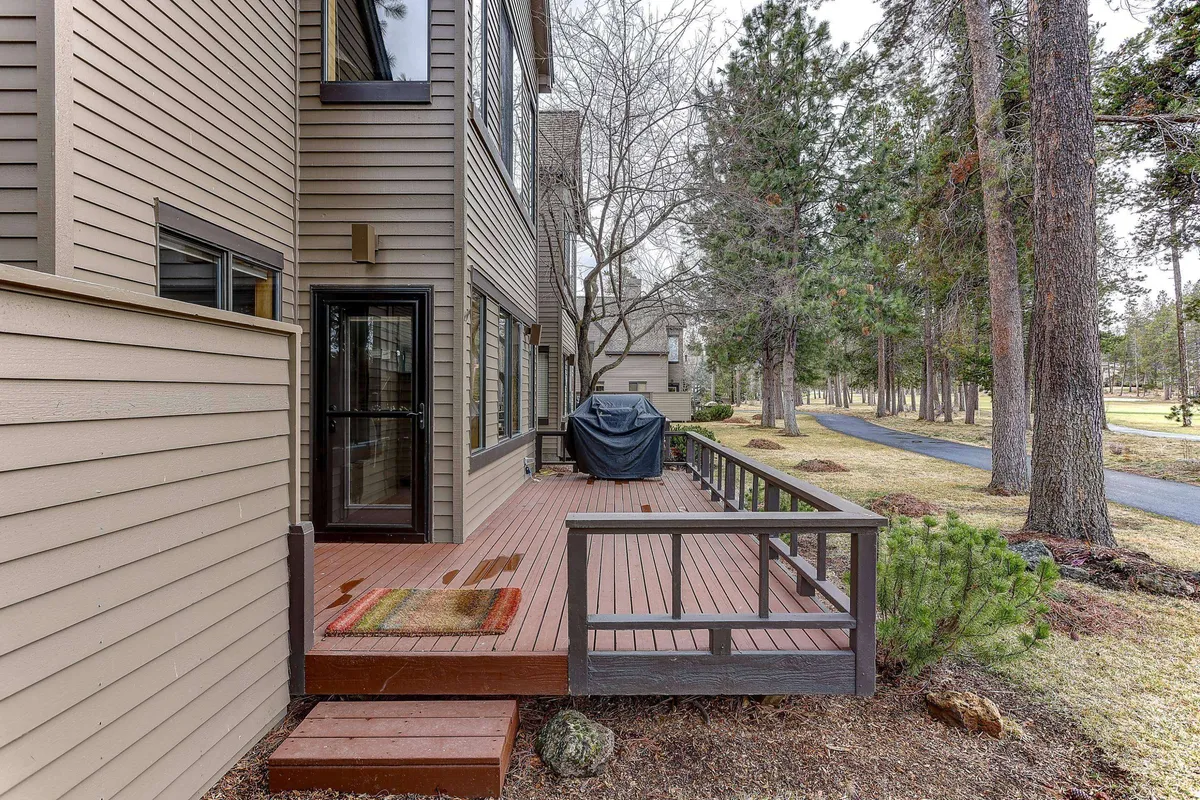 This exterior image highlights a spacious deck area equipped with a grill and surrounded by natural greenery. The scene invites outdoor dining, family gatherings, or quiet relaxation, all with the ambiance of being immersed in nature.