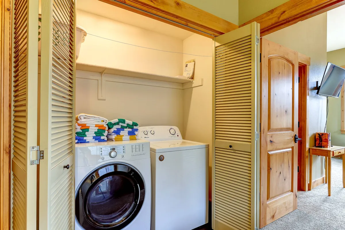 A tidy laundry area featuring a washing machine, dryer, and neatly stacked towels. The setting is practical and inviting, suggesting convenience for active guests returning from outdoor excursions.