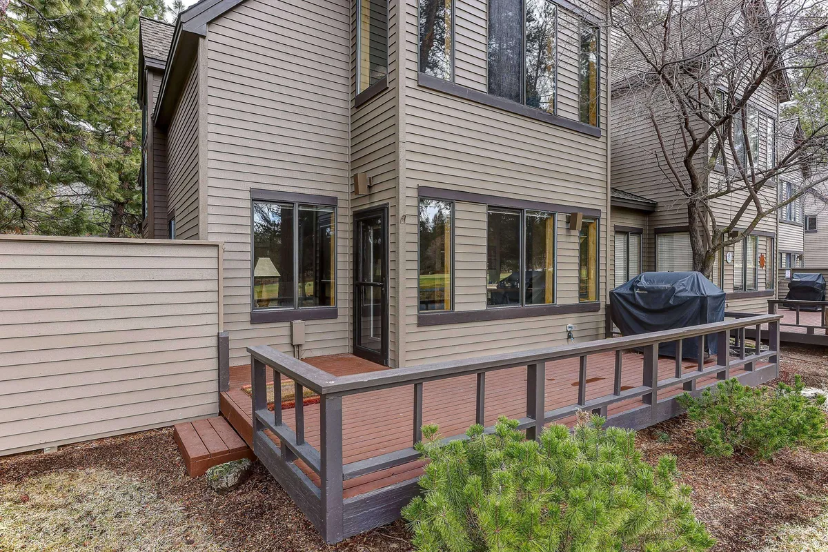 A spacious deck area with large windows looks out onto lush greenery, inviting guests to relax outdoors. The setting is ideal for outdoor dining, barbecuing, or simply enjoying the peaceful natural surroundings.