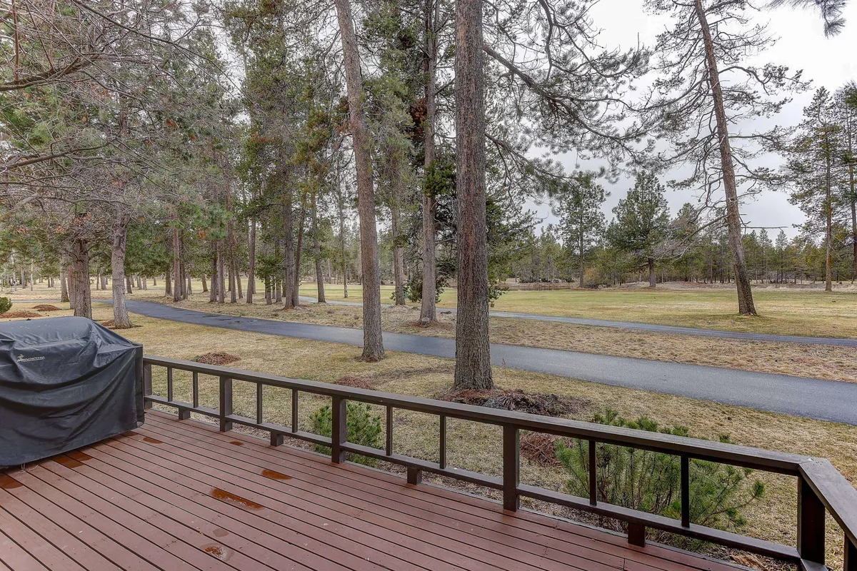 A peaceful wooden deck is surrounded by trees and features a pathway leading away, offering views of nature and opportunities for outdoor relaxation. The mood is calm, inviting, and ideal for enjoying the outdoors, with possibilities for watching wildlife or relaxing with a book.